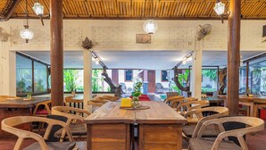 Ein Restaurant mit Holztischen und -stühlen, Backsteinwänden und hängenden Lampen.