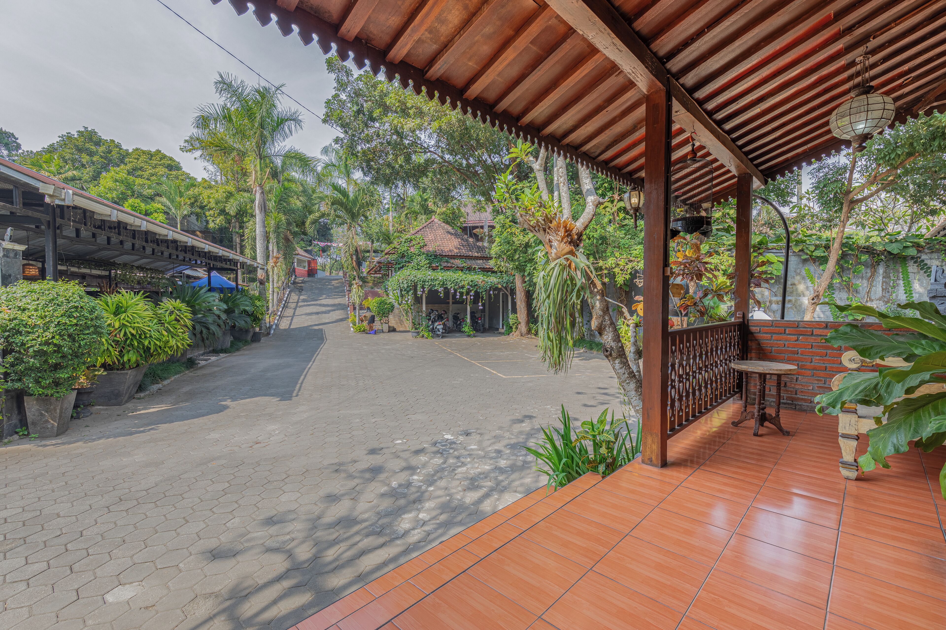 A covered outdoor area with a tiled floor, a small table, and potted plants.