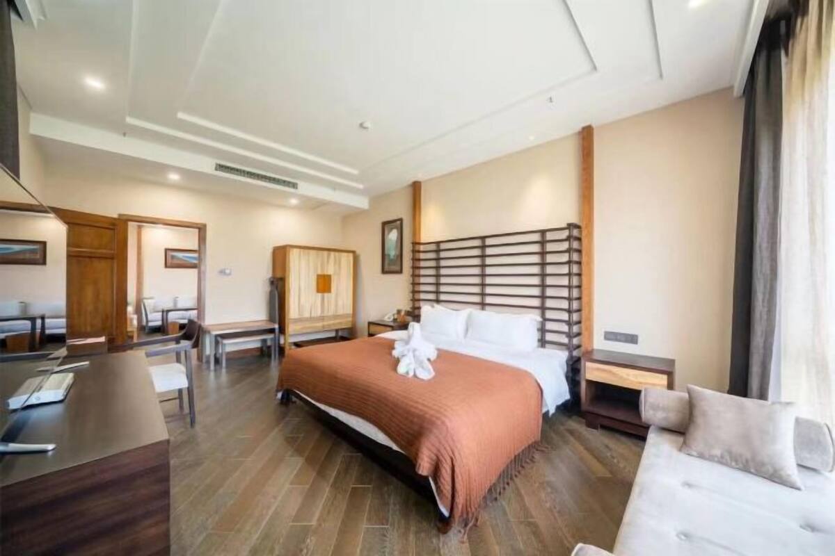 A hotel room with a large bed, a desk, and a sofa.