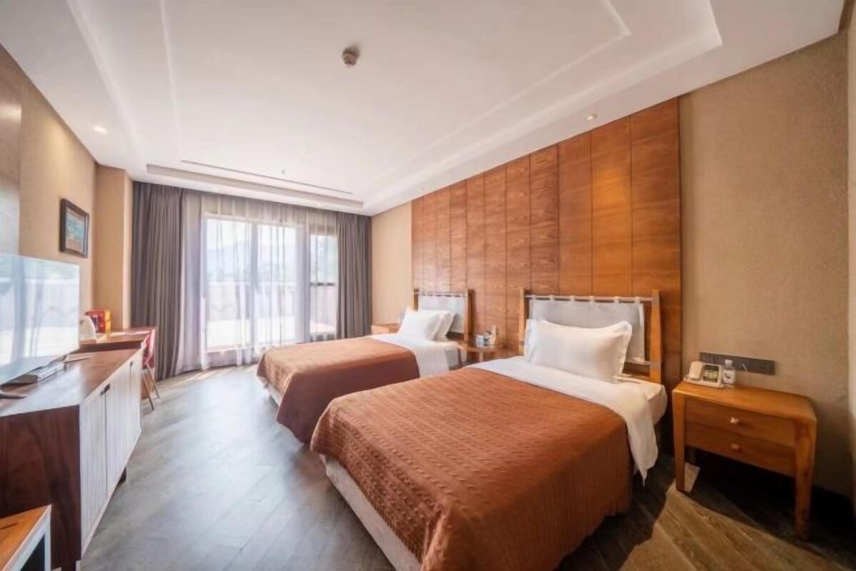 A hotel room with two beds, a desk, and a TV.
