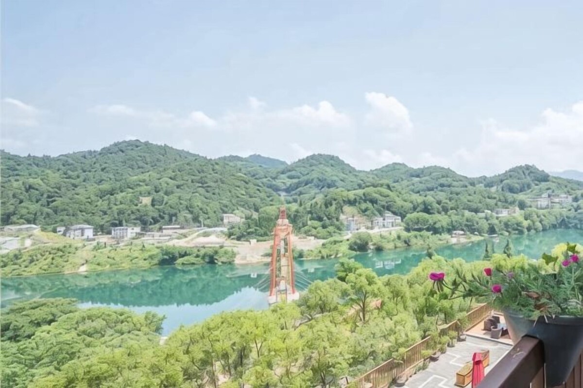 A view of a river with a bridge, surrounded by greenery and hills.