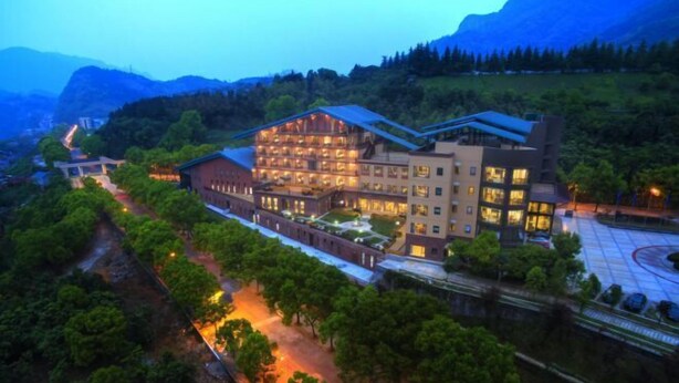 A large hotel with multiple floors, surrounded by lush greenery and mountains in the background. - Geheyan Hotel (Changyang)