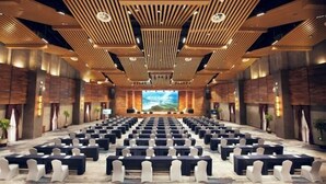 A conference room with rows of tables and chairs, wooden slatted ceiling, and a large screen at the front. - Geheyan Hotel (Changyang)