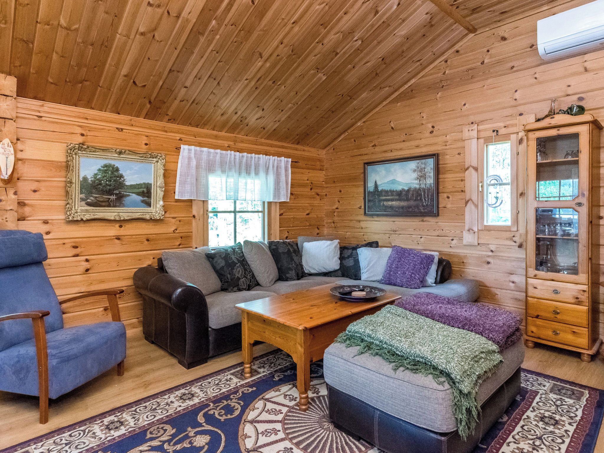 Ein gemütliches Blockhaus-Interieur mit einer Couch, einem Sessel und einem Holztisch.