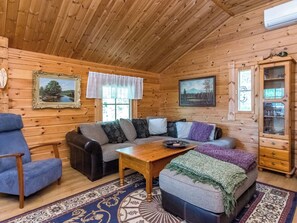 A cozy log cabin interior with a sofa, armchair, and a wooden coffee table. - Kärppälä by Interhome (Savonlinna)