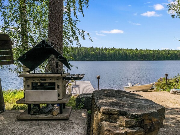 A lakeside cabin with a stone structure, a dock, and a boat.