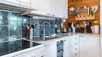Una cocina moderna con una estufa negra, armarios blancos y un salpicadero de mármol.