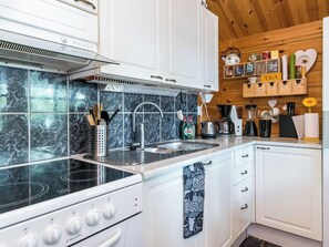 Una cocina moderna con una estufa negra, armarios blancos y un salpicadero de mármol.