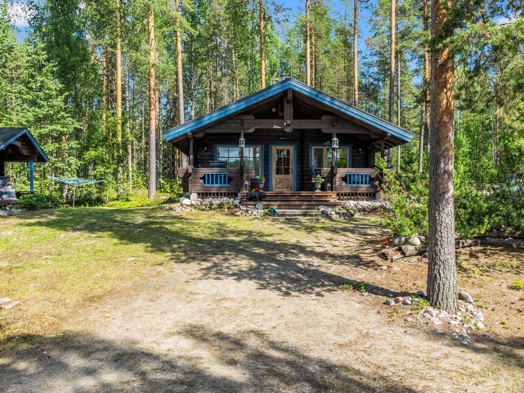 A cabin with a porch, surrounded by tall trees.