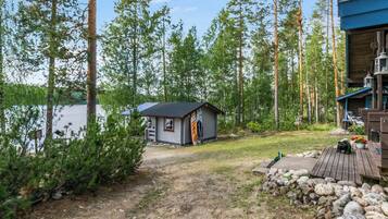 A cabin with a small porch, surrounded by trees and a lake.
