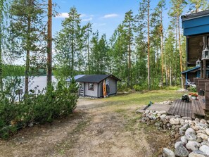 A cabin with a small porch, surrounded by trees and a lake. - Kärppälä by Interhome (Savonlinna)