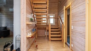 Un intérieur en bois avec un escalier, un petit coin salon et une porte donnant sur l’extérieur.