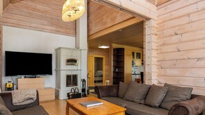 Un salon chaleureux avec un plafond en bois, une cheminée, un téléviseur et un canapé.