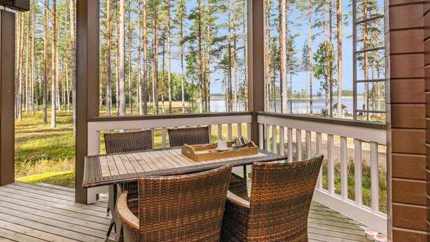 Une terrasse extérieure couverte, aménagée avec des meubles en osier, une table et un barbecue.