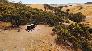A remote cabin surrounded by dense trees and hills.