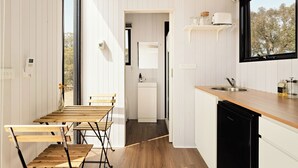 Moderni keittiö, jossa on puuhuonekalut, astianpesukone ja ikkuna, josta avautuu näkymä puita kohti.