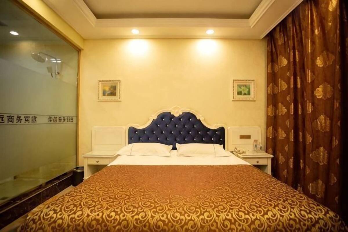 A hotel room with a large bed, bedside tables, a mirror, and a curtain.