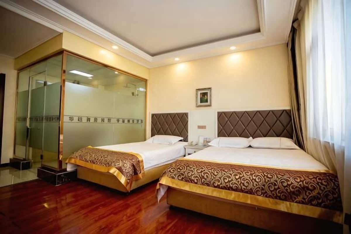 A hotel room with two beds, a glass door, and a framed picture on the wall.