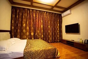 Une chambre d’hôtel équipée d’un lit, d’un téléviseur et d’un écran plat fixé au mur, ainsi que d’une grande fenêtre avec des rideaux.