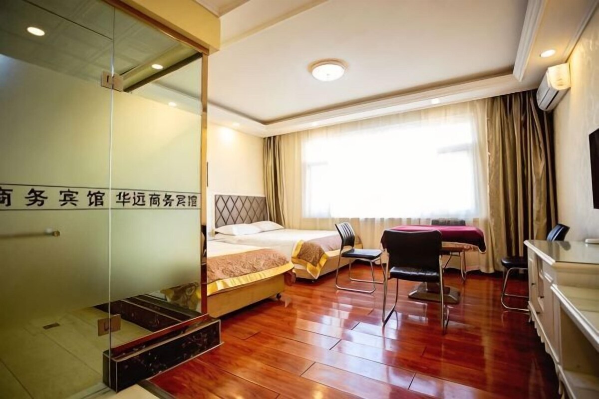 A hotel room with a bed, a desk, a chair, a TV, and a window with curtains.
