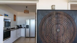 A modern kitchen with white cabinets, a stainless steel refrigerator, and a microwave. - Villa Malinina, swimming pool, sea view (Les Anses-d'Arlet.)