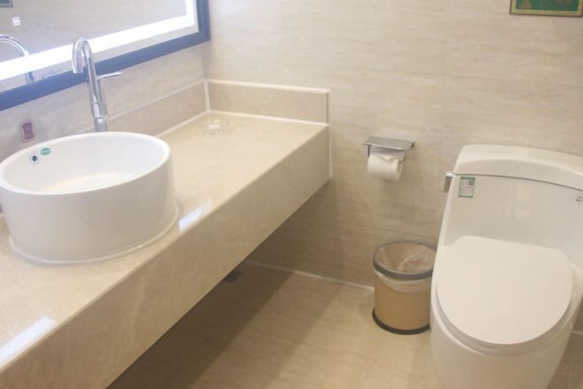Une salle de bain équipée d’un lavabo, de toilettes et d’une poubelle.