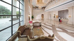 A spacious lobby with a grand chandelier, a reception desk, and a seating area with a sofa and coffee table. - Vienna Hotel (Foshan Qiandeng Lake) (Foshan)