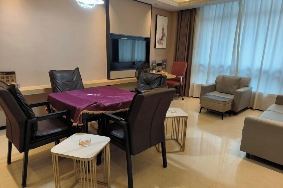 Une chambre d’hôtel équipée d’une table à manger, de chaises, d’un canapé, d’une télévision et d’une fenêtre avec des rideaux.