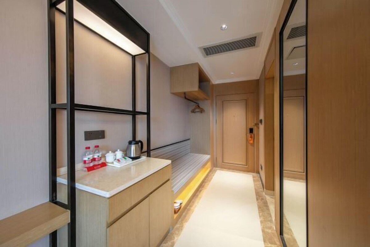 Une salle de bain d’hôtel moderne, dotée d’une douche à parois de verre, d’un meuble-lavabo avec miroir et d’un porte-serviettes.