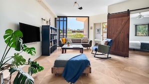 A modern living room with a large TV, a bookshelf, a sofa, a coffee table, and a sliding barn door. - Hasharon Rooftop Oasis by Sea N' Rent (Ramat Hasharon)