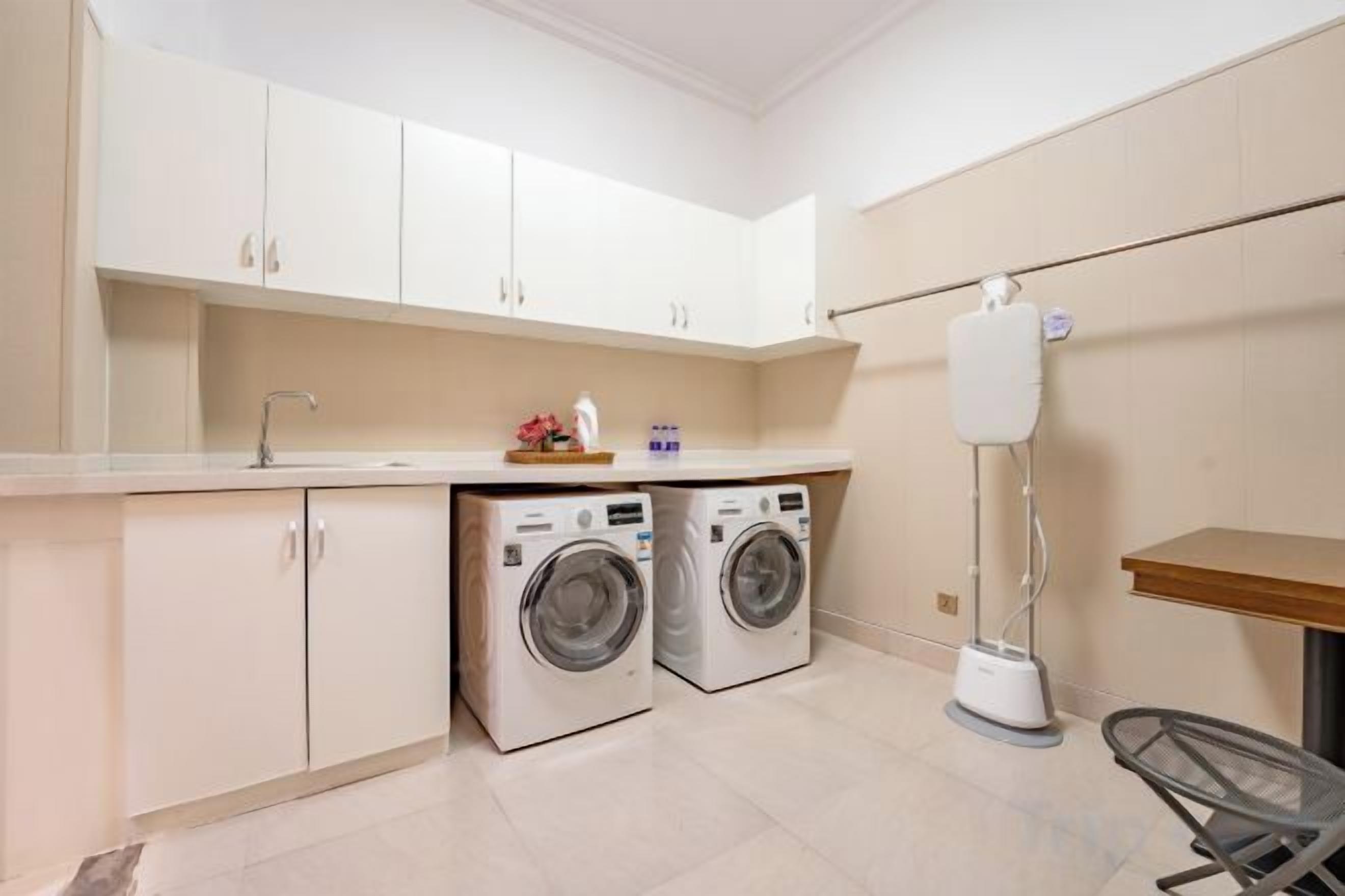 A laundry area with two washing machines, a sink, and a floor lamp.