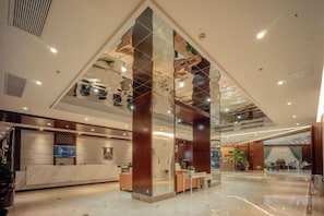 A spacious lobby with a reception desk, seating area, and a large glass partition. - Qixin Hotel (Hangzhou)