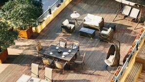 Una terrazza con mobili da esterno, tra cui un tavolo e sedie, e una poltrona sospesa.