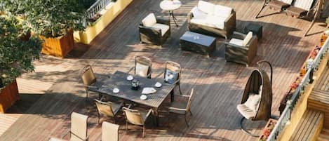 En udendørs terrasse med spiseplads, siddepladser og udsigt til vandet.