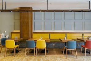 A restaurant with a long counter, multiple seating options including booths and chairs, and a large window with a view. - Qixin Hotel (Hangzhou)
