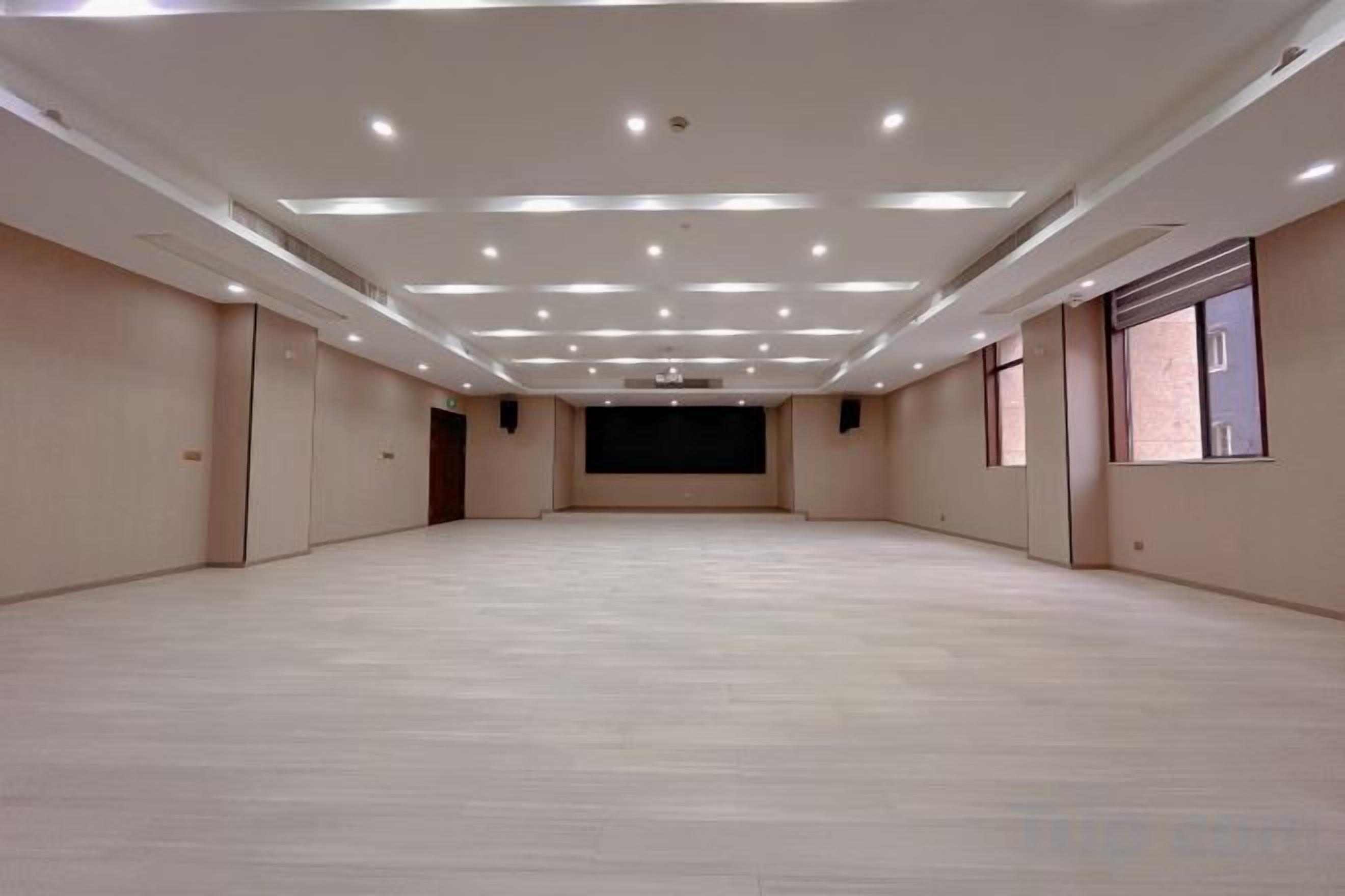 A large, empty room with a high ceiling and multiple windows.