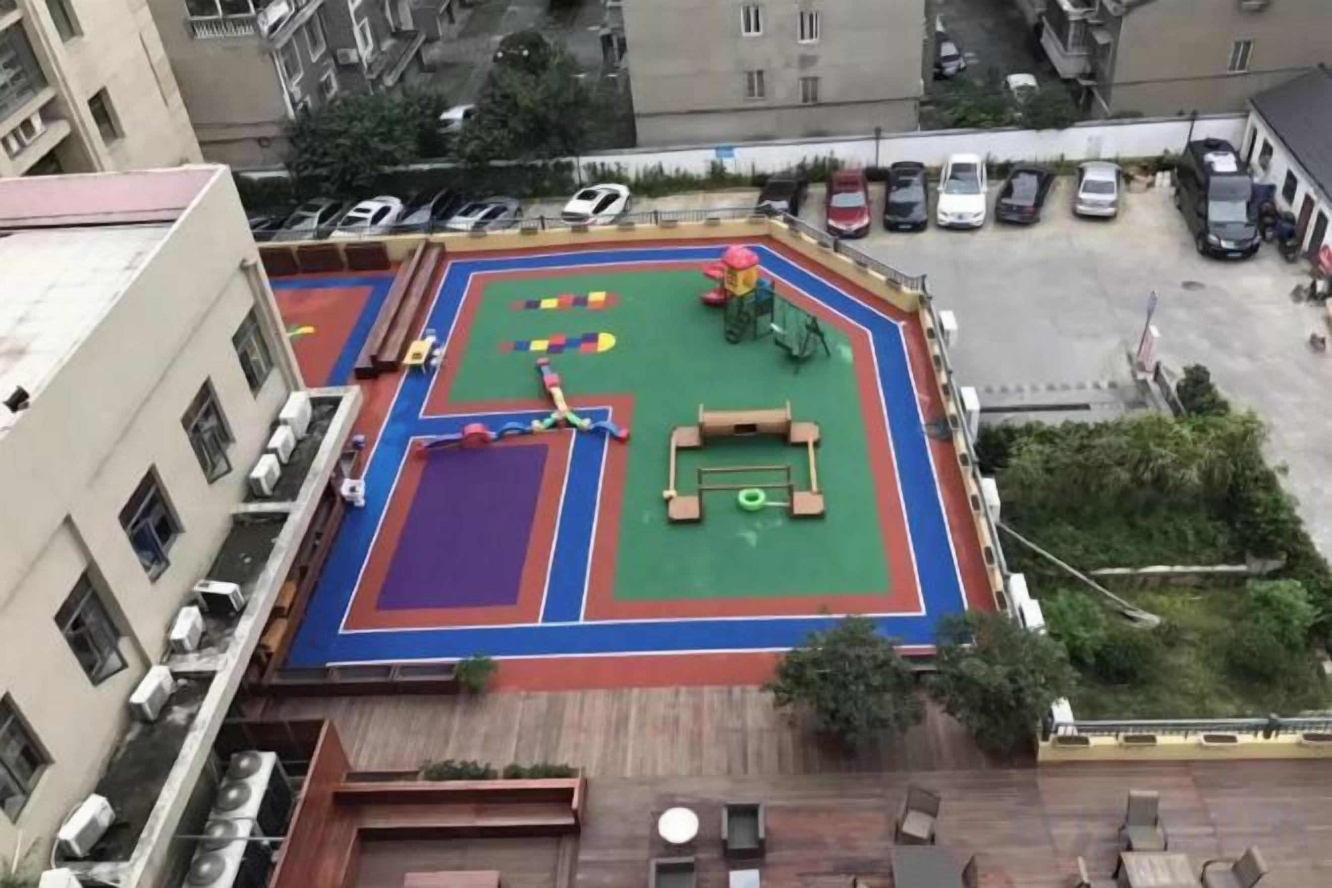 A rooftop playground with a basketball court, climbing wall, and seating area.