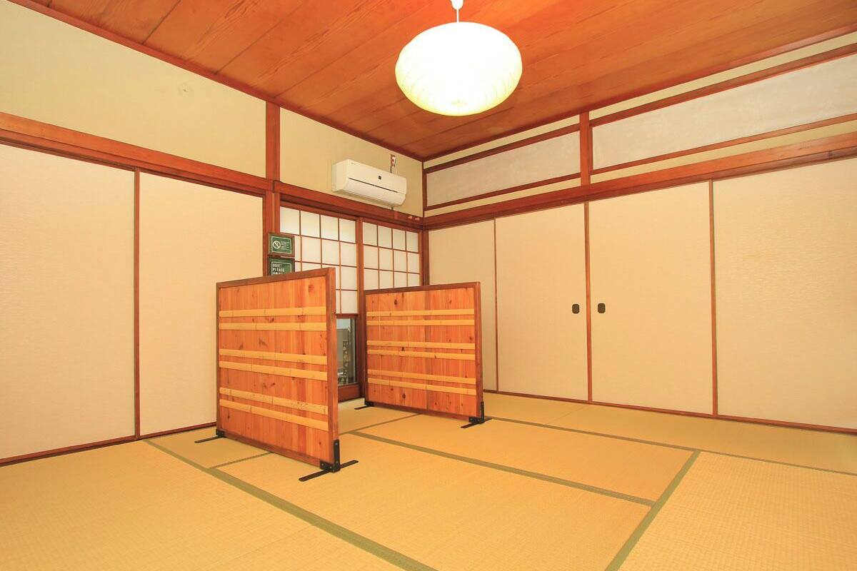 A traditional Japanese room with tatami flooring, sliding doors, and a ceiling fan.