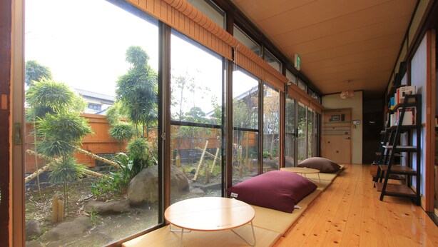 Una habitación con suelo de tatami, una mesa baja y vistas a un jardín a través de amplios ventanales.