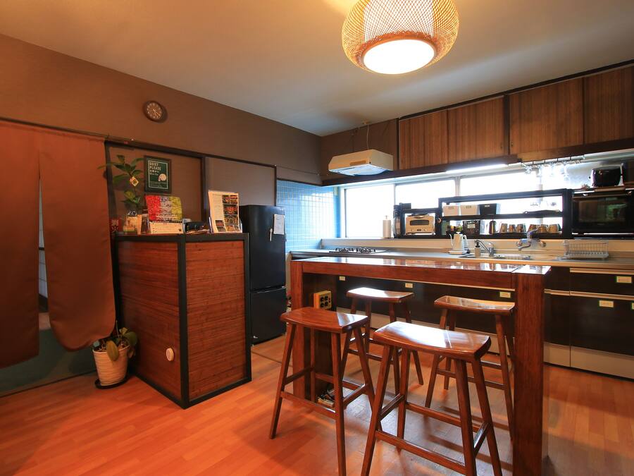 Una cocina moderna con armarios de madera, una isla central con taburetes, horno empotrado y un amplio ventanal que proporciona luz natural.