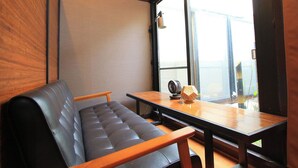 Una habitación moderna con un sofá de cuero negro, una mesa de madera y un ventanal con vistas al exterior.