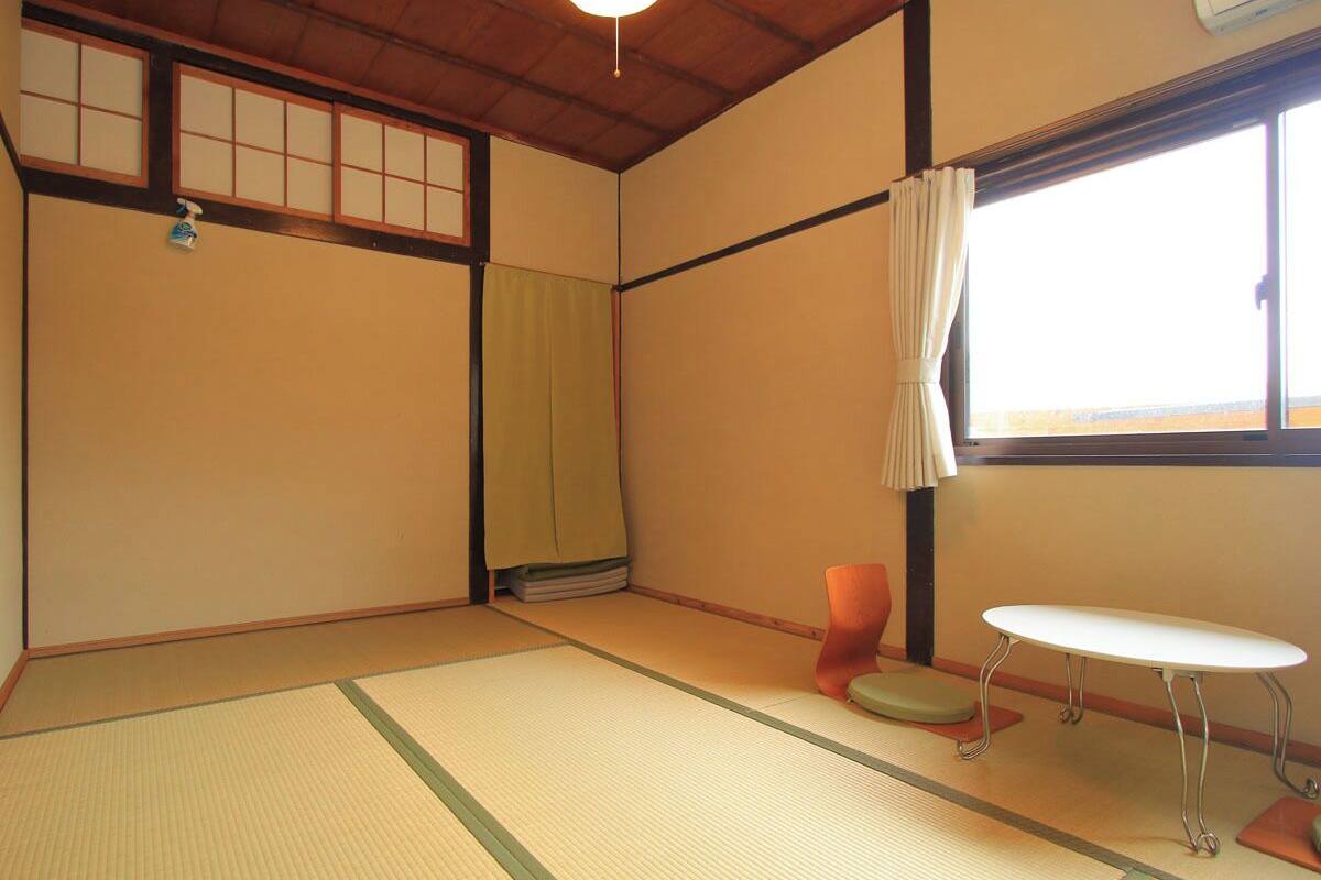 A traditional Japanese room with tatami flooring, a low table, a cushion, and a sliding door.