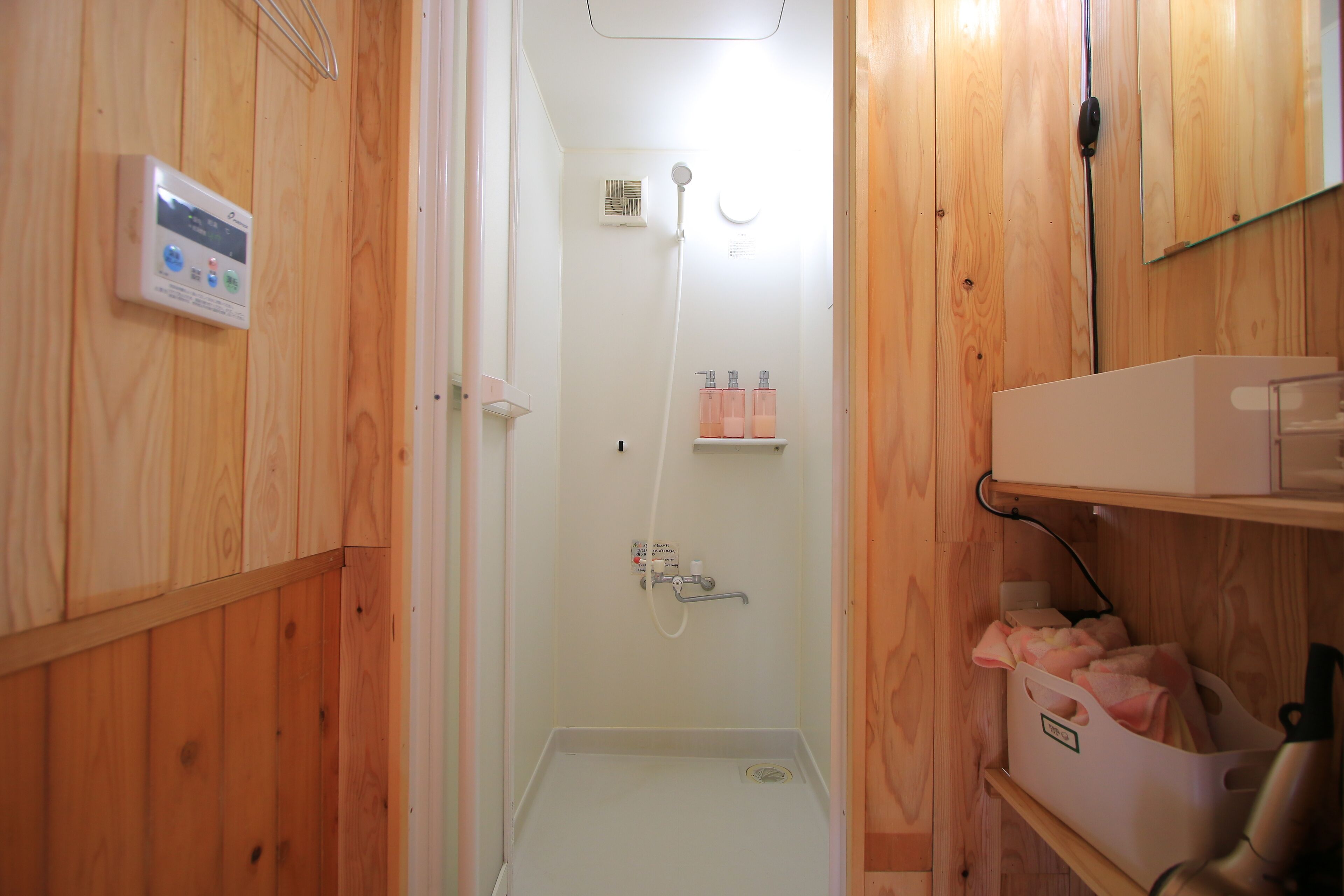Un baño con paneles de madera, una ducha, un panel de control y estantes de almacenamiento.