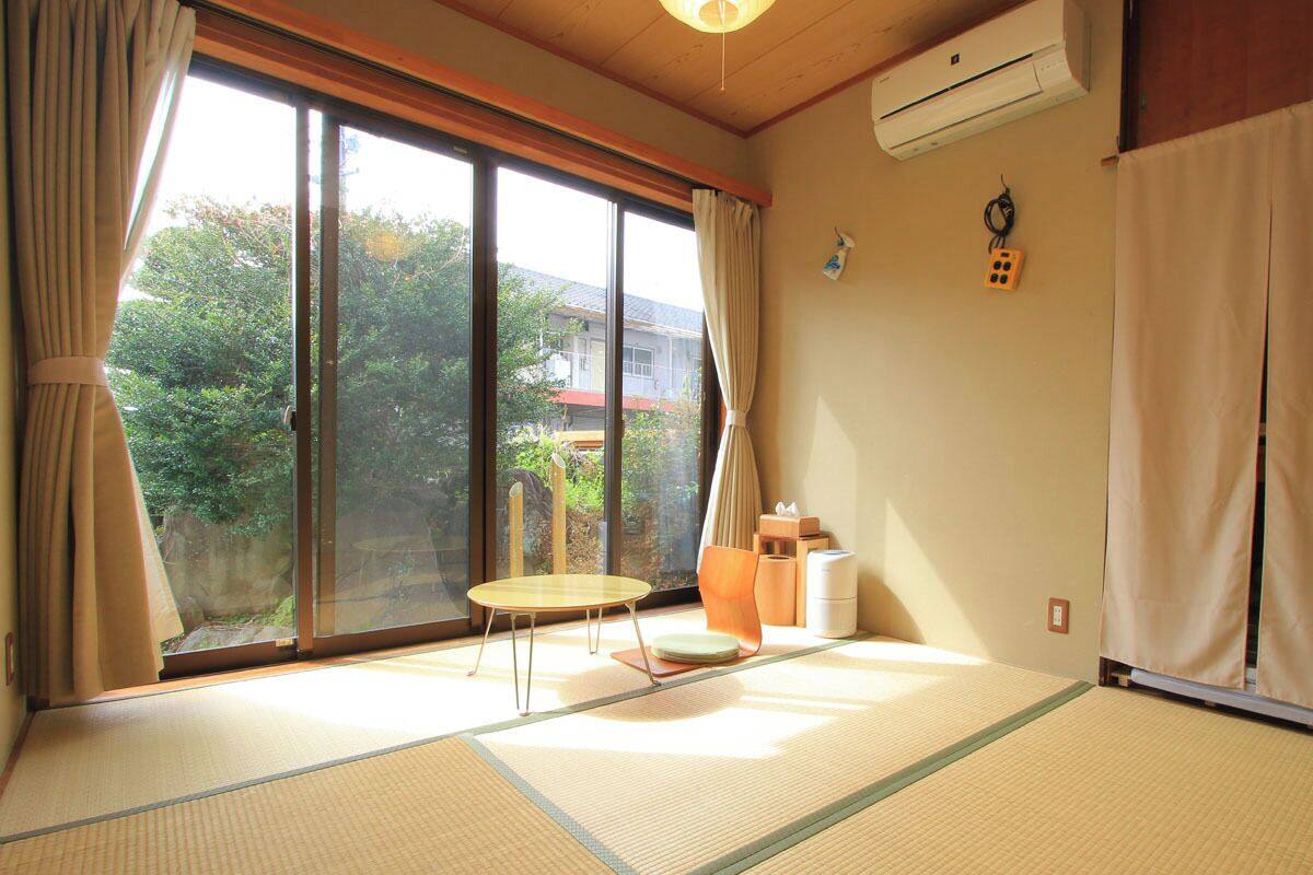 A tatami mat room with a sliding door, a small table, and a futon bed.