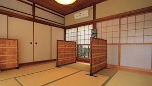 Una habitación tradicional japonesa con suelo de tatami, puertas correderas y un ventilador de techo.