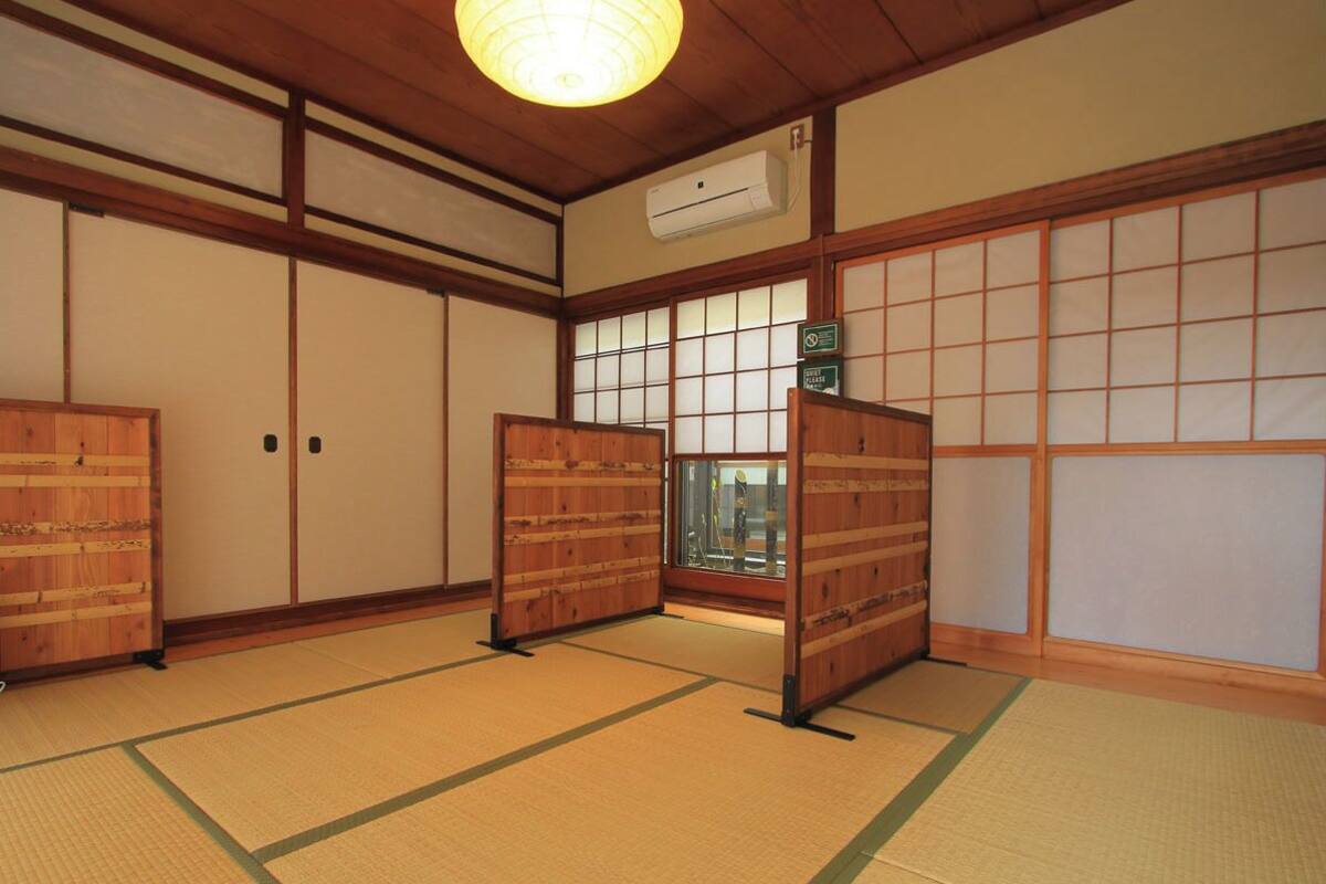 A traditional Japanese room with tatami flooring, sliding doors, and a ceiling fan.