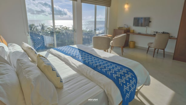 Habitación de hotel con una cama grande, dos sillas, un escritorio y vistas a la ciudad.