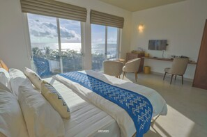 A hotel room with a large bed, two chairs, a desk, and a view of the city. - 50 By The Sea (Dehiwala-Mount Lavinia)