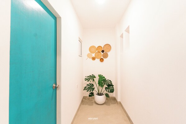A hallway with a turquoise door, a potted plant, and a wall-mounted circular decoration. - 50 By The Sea (Dehiwala-Mount Lavinia)