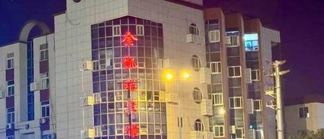 Un edificio de varios pisos con un letrero rojo llamativo en la parte superior, amplias ventanas y un diseño arquitectónico moderno.